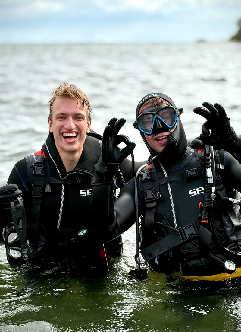 Begeleide duikers in het water lachen en geven een ok-signaal